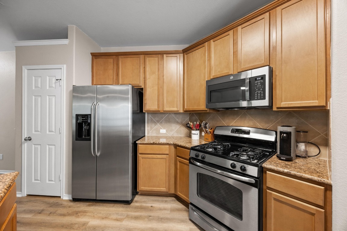 1310 West Parmer Lane, Unit 9B Austin, TX 78727 - Photo 11 of 38 a kitchen with stainless steel appliances granite countertop a stove microwave refrigerator and sink