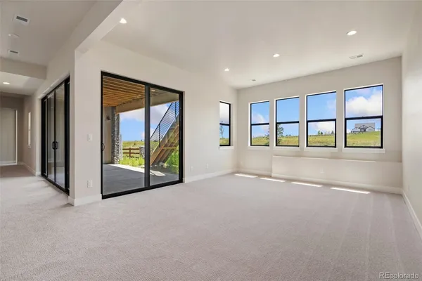 a view of an empty room with a window and a kitchen