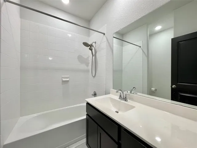 a bathroom with a sink double vanity granite tub shower and a mirror