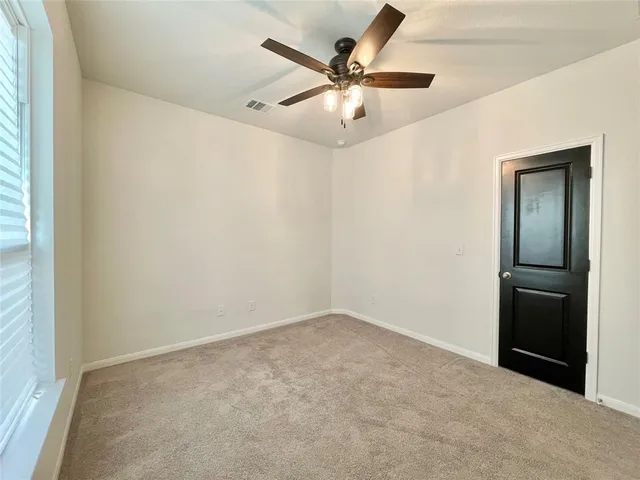 an empty room with a chandelier fan and windows