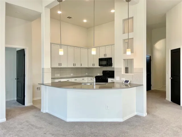 a view of a kitchen with kitchen island a sink stainless steel appliances and cabinets