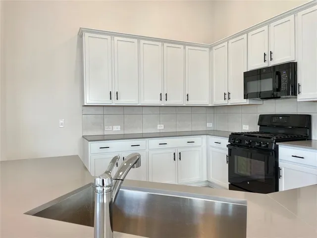 a kitchen with granite countertop white cabinets and a stove
