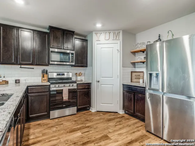 a kitchen with granite countertop a refrigerator stove and microwave