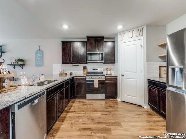 a large kitchen with stainless steel appliances granite countertop a stove refrigerator and a sink