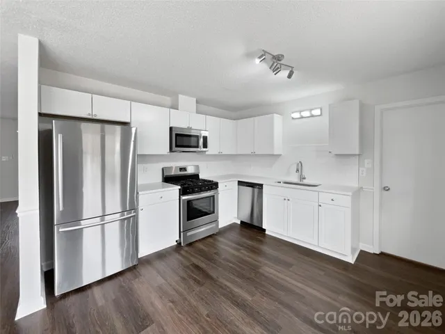 a kitchen with a refrigerator a stove top oven a sink and cabinets