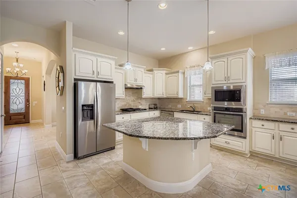 a kitchen with stainless steel appliances granite countertop a refrigerator a stove a sink and a refrigerator