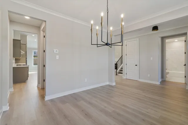 a view of an empty room with wooden floor and a kitchen