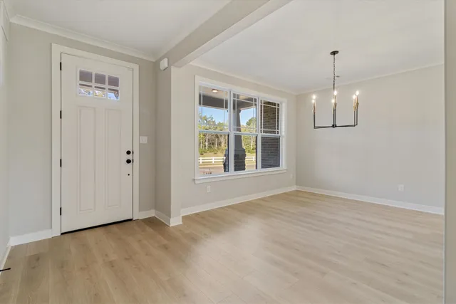 a view of an empty room with window and chandelier fan