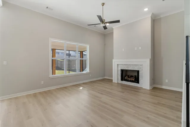 a view of an empty room with wooden floor fireplace and a window