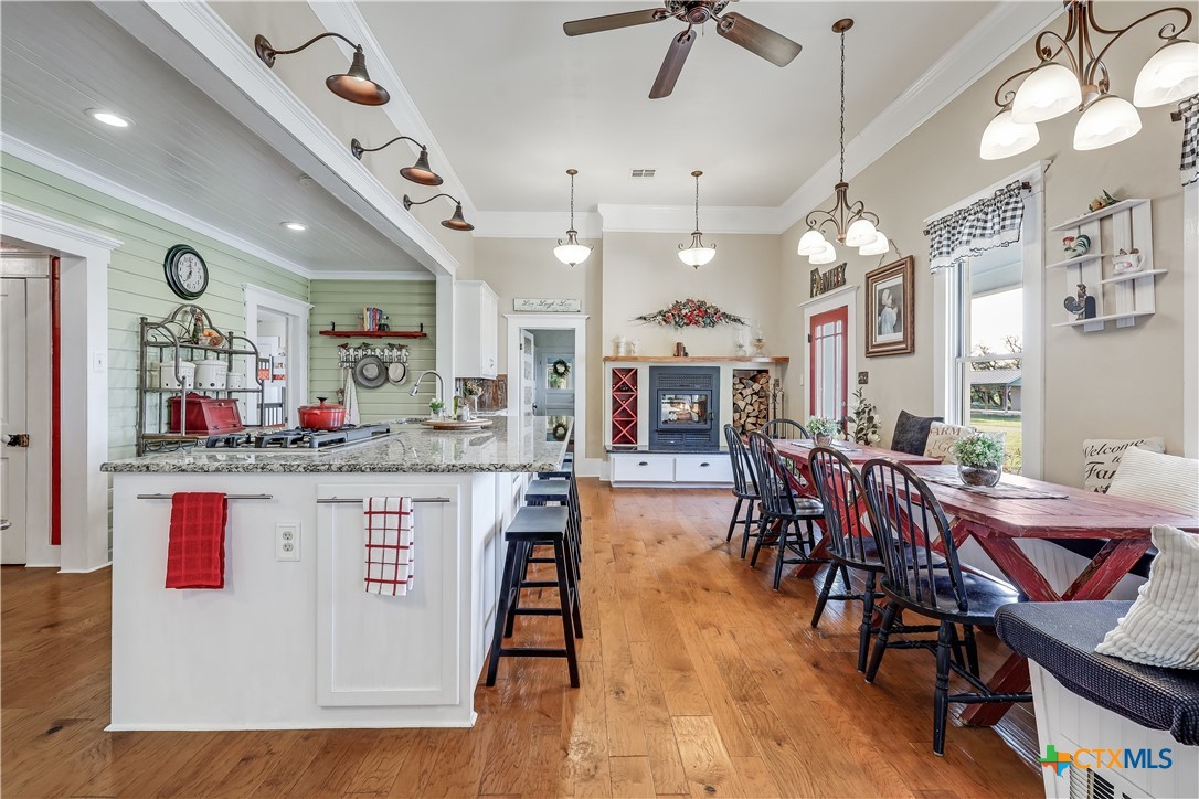13471 Cedar Valley Road Salado, TX 76571 - Photo 13 of 41 a kitchen with stainless steel appliances granite countertop a kitchen island a stove a dining table and chairs with wooden floor