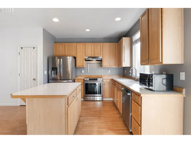 a kitchen with stainless steel appliances granite countertop a stove a sink a refrigerator and a refrigerator