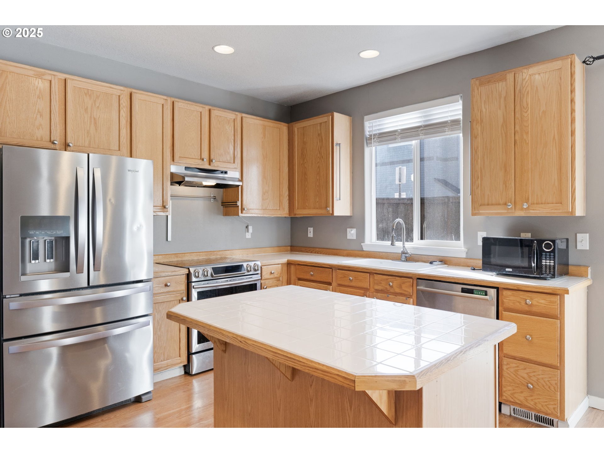 887 Southwest 198th Place Beaverton, OR 97003 - Photo 8 of 33 a kitchen with stainless steel appliances granite countertop a refrigerator a sink dishwasher a stove and white countertops with wooden floor