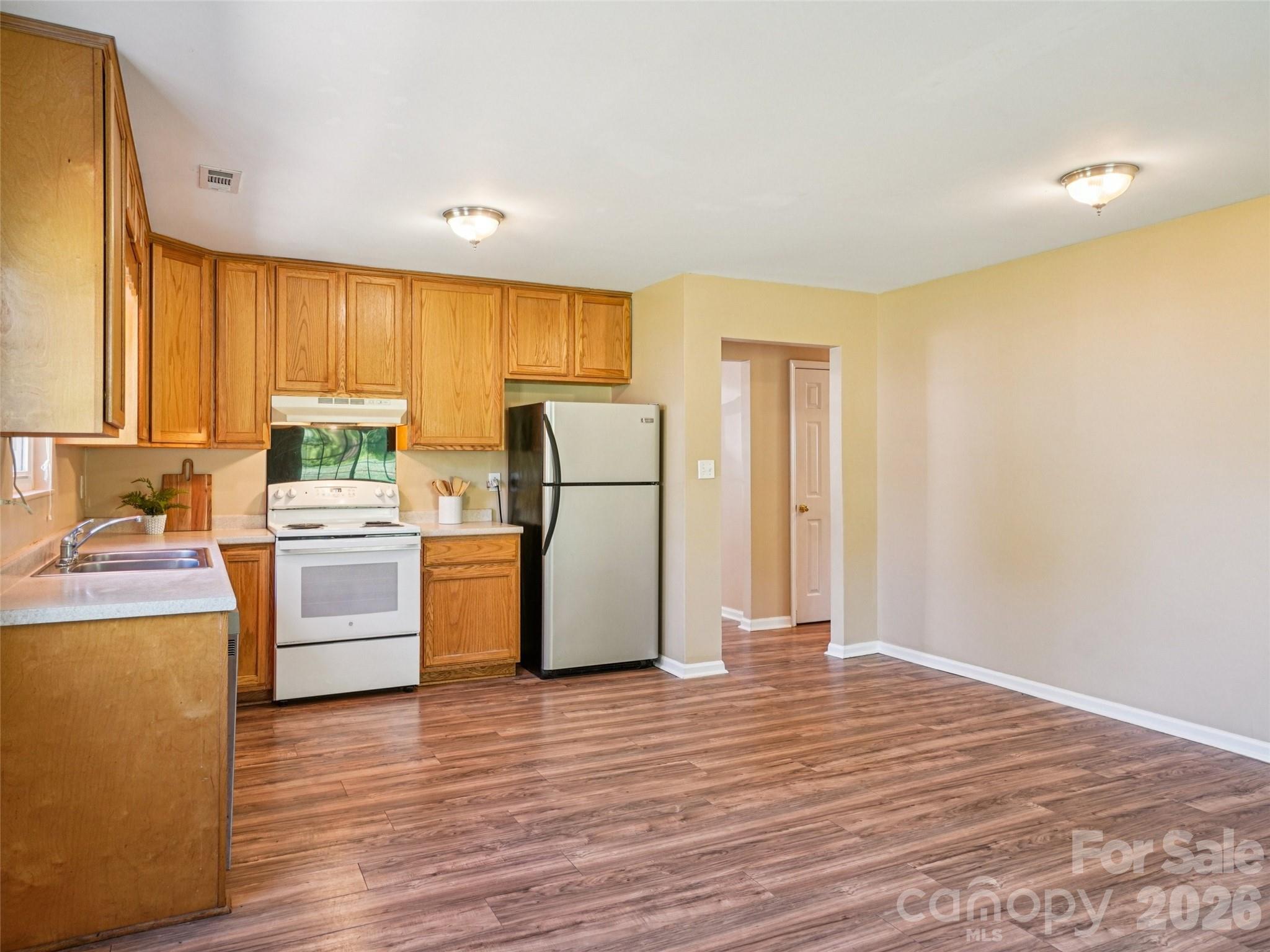 88 Lees Creek Road Asheville, NC 28806 - Photo 9 of 29 a kitchen with a refrigerator a stove top oven a sink dishwasher and a dining table with wooden floor