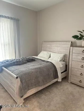 a bed sitting in a bedroom next to a window and dresser