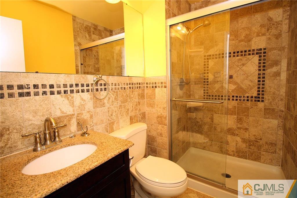 5203 Hana Road Edison, NJ 08817 - Photo 19 of 25 a bathroom with a granite countertop sink toilet a mirror and shower