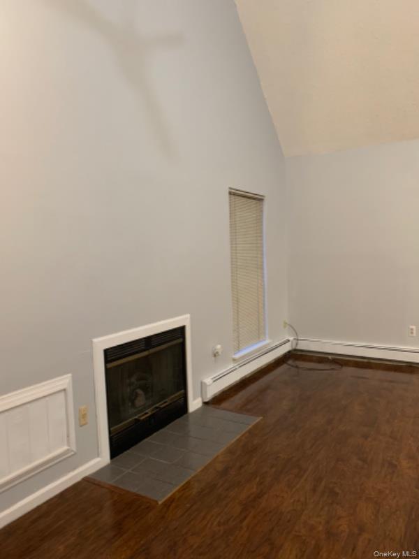 20 Fox Ridge Woodridge, NY 12789 - Photo 4 of 24 Unfurnished living room featuring a fireplace with flush hearth, dark wood-type flooring, high vaulted ceiling, and a baseboard heating unit
