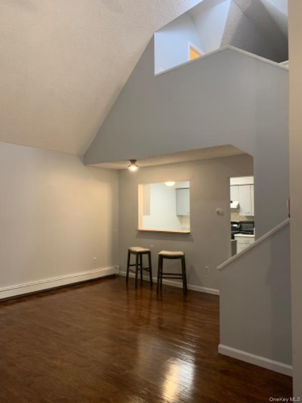 20 Fox Ridge Woodridge, NY 12789 - Photo 5 of 24 Unfurnished living room featuring baseboard heating, dark wood-type flooring, high vaulted ceiling, and a textured ceiling