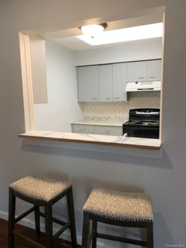 20 Fox Ridge Woodridge, NY 12789 - Photo 6 of 24 Kitchen with black / electric stove, backsplash, under cabinet range hood, and a kitchen bar