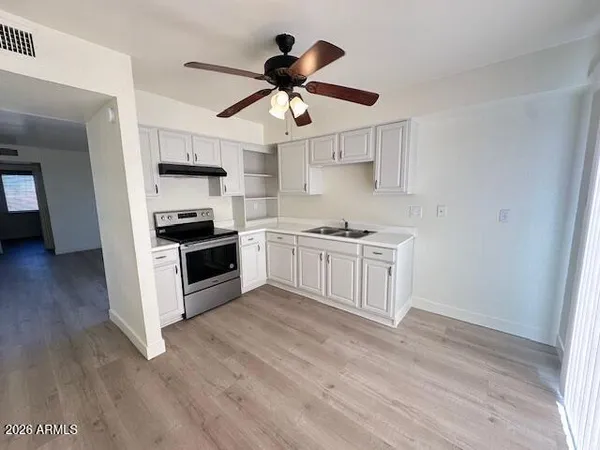 a kitchen with stainless steel appliances a stove a sink and white cabinets