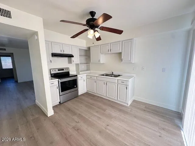 a kitchen with stainless steel appliances a stove a sink and white cabinets