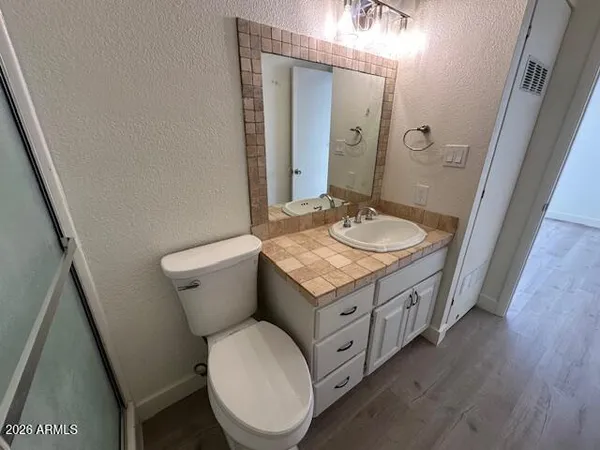a bathroom with a granite countertop toilet sink and mirror