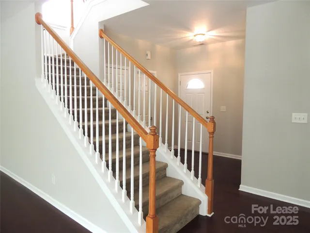 a view of staircase with lots of frames on wall and wooden floor