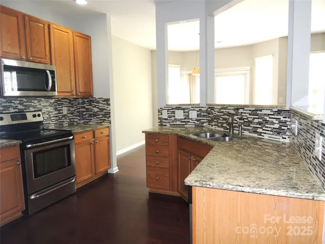 a kitchen with stainless steel appliances granite countertop a stove a sink and a microwave