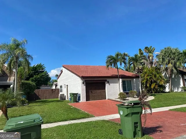 a front view of a house with a yard and palm trees