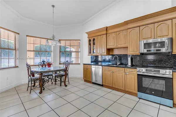 a kitchen with stainless steel appliances granite countertop a stove top oven a sink a dining table and chairs