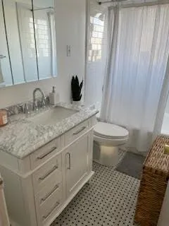 a bathroom with a granite countertop sink a toilet and a mirror