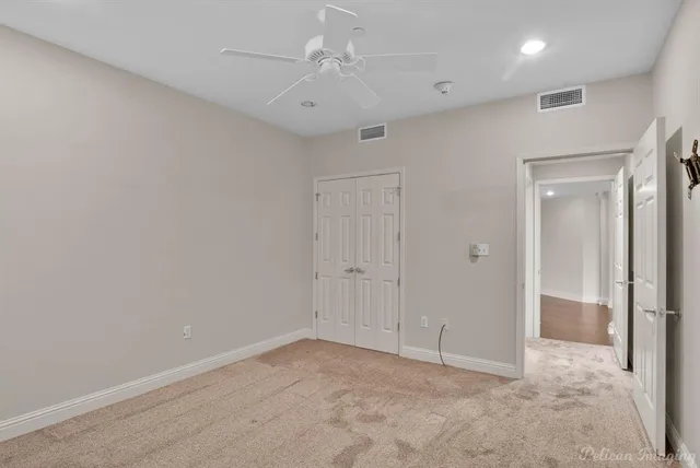 an empty room with closet and ceiling fan