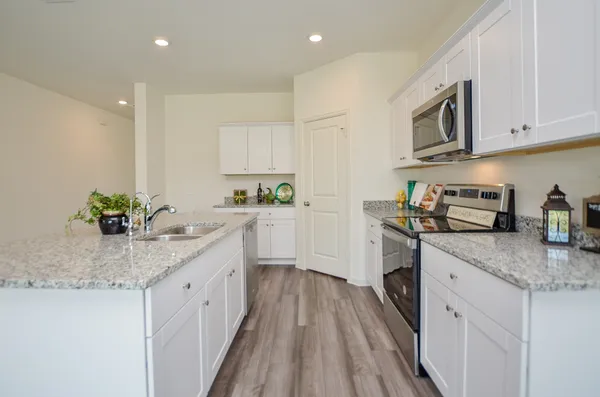 a kitchen with granite countertop stainless steel appliances a sink dishwasher stove refrigerator and microwave with wooden floor