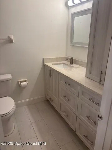 a bathroom with a granite countertop sink toilet and mirror