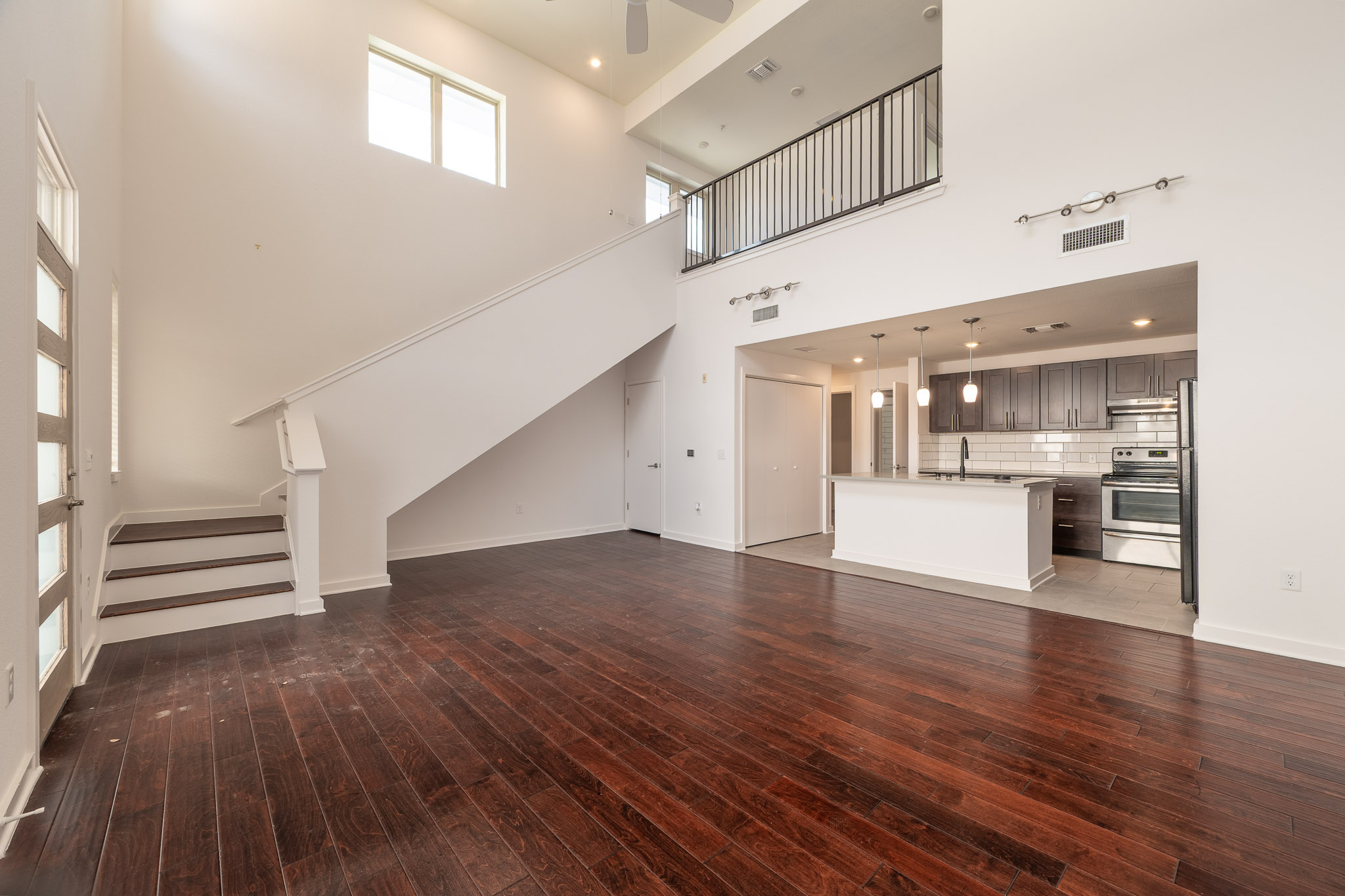 6700 Menchaca Road, Unit 20 Austin, TX 78745 - Photo 3 of 20 A spacious living area with soaring ceilings seamlessly integrates with a modern kitchen and upper-level balcony.