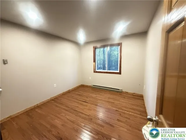 an empty room with wooden floor and window