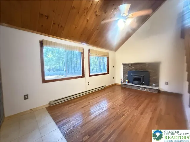 an empty room with wooden floor fireplace and windows