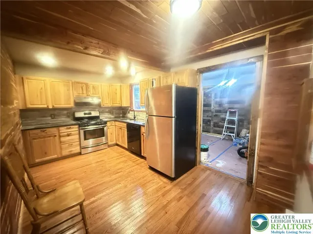 a kitchen with stainless steel appliances granite countertop a refrigerator a stove and a wooden floors