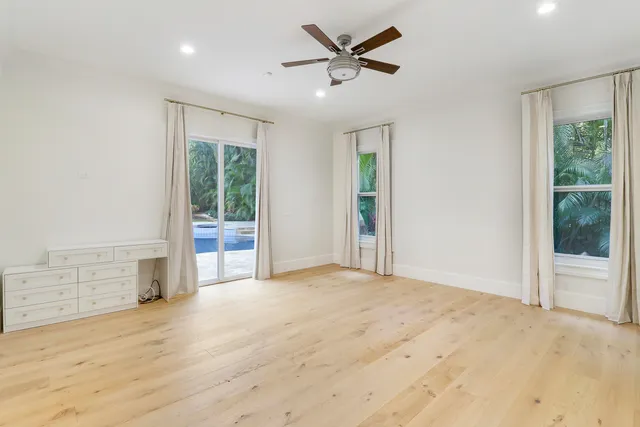 an empty room with a ceiling fan and kitchen view