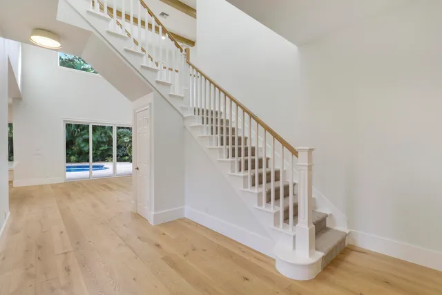 a large white room with kitchen view and large windows