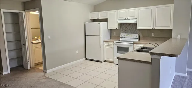 a kitchen with stainless steel appliances a refrigerator sink and white cabinets