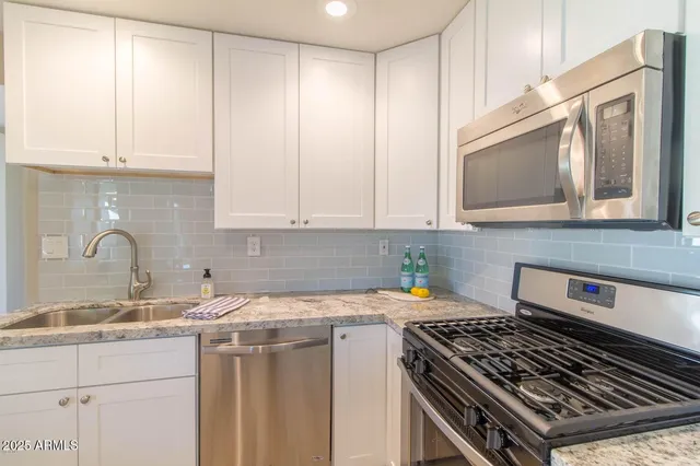 a kitchen with stainless steel appliances granite countertop a stove a sink and a white cabinets