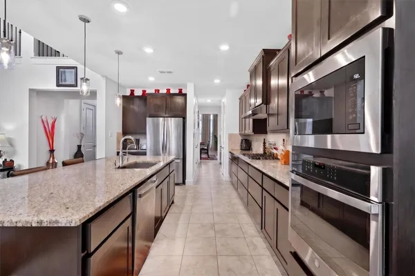 a kitchen with stainless steel appliances kitchen island granite countertop a stove a sink and a refrigerator
