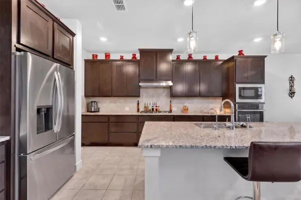 a kitchen with stainless steel appliances granite countertop a sink refrigerator and microwave