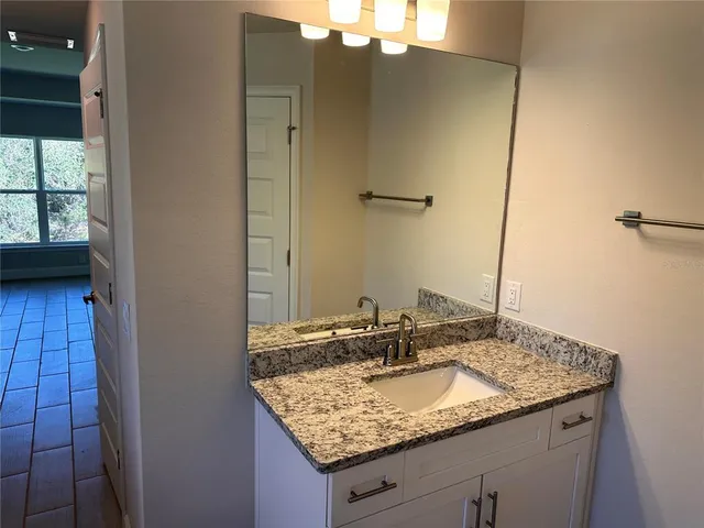 a bathroom with a granite countertop sink and a mirror
