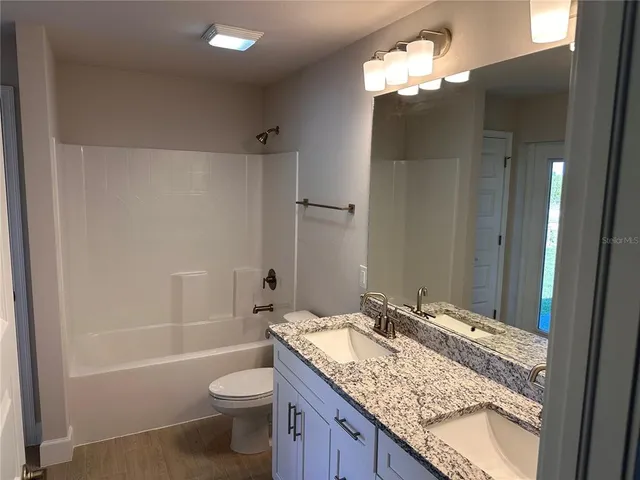 a bathroom with a granite countertop sink toilet and shower