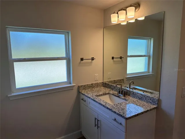 a bathroom with a granite countertop sink a mirror and a window