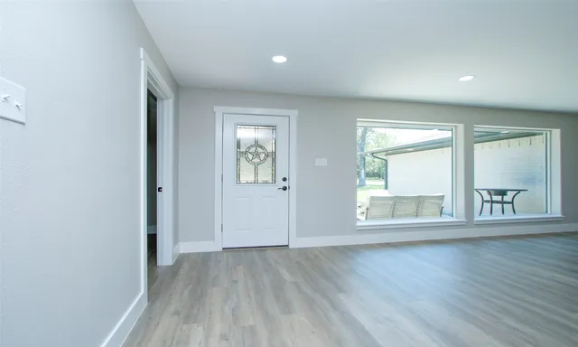an empty room with wooden floor and windows