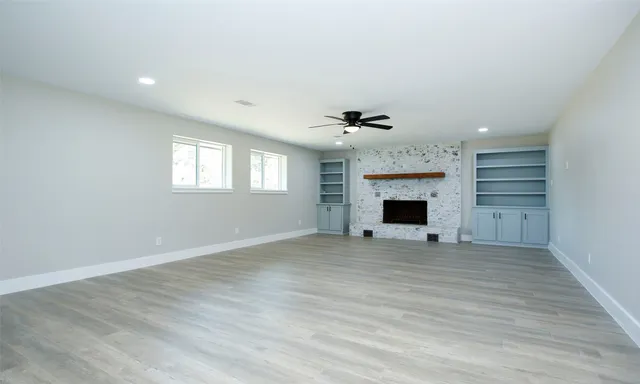 an empty room with windows and fireplace