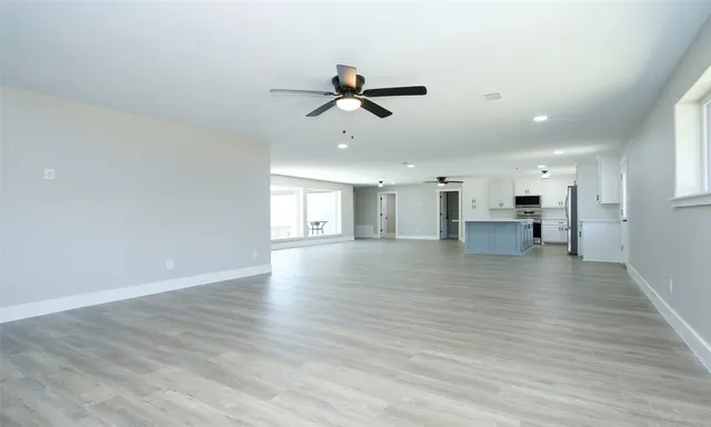 a view of a room with wooden floor and a ceiling fan