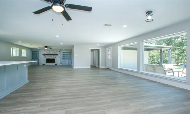 an empty room with wooden floor fan and windows